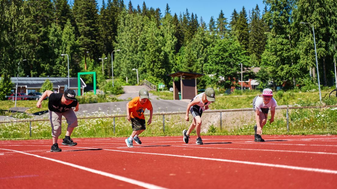 Lapset urheilukentällä juoksukilpailuun lähdössä