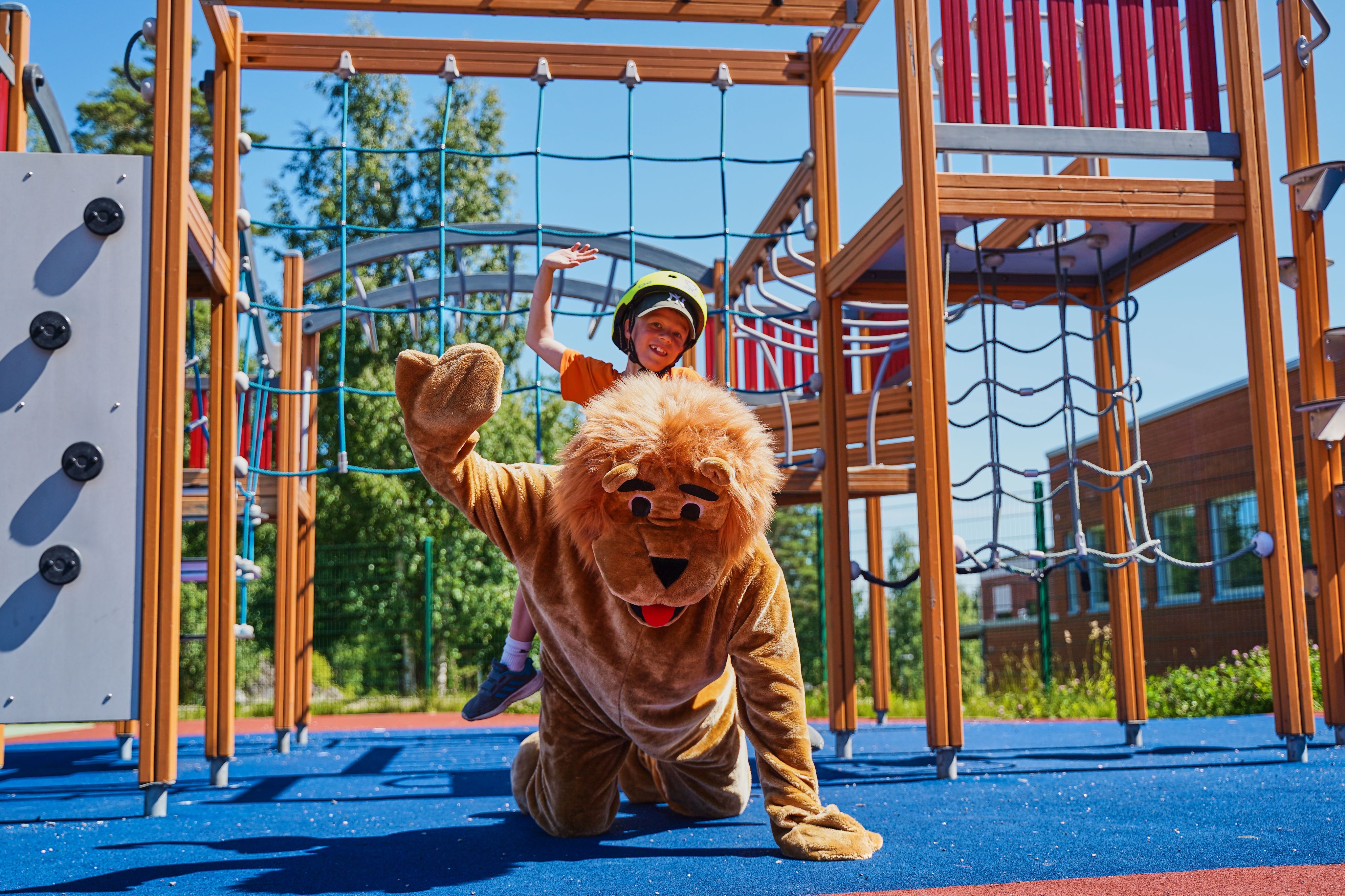 Lapsi leijonan selässä kiipeilytelineen alla